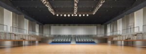 Explore a theater acoustic treatment project in Bangladesh using grooved wood, upholstered, and suspended polyester fiber acoustic panels for reverberation control and acoustic comfort.